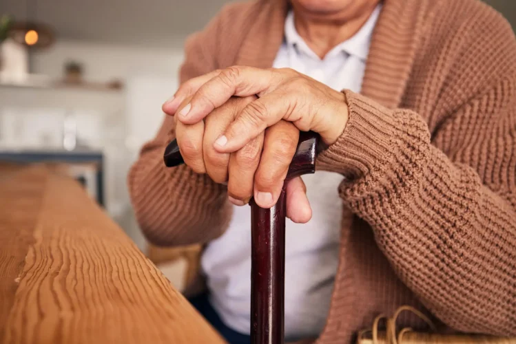 Closeup, hands and cane of person with disability, arthritis and aid of osteoporosis, parkinson or